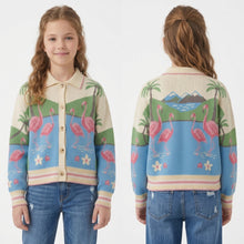 Load image into Gallery viewer, A young girl modeling a colorful knit cardigan sweater, shown from both the front and back views against a plain white studio background. The cardigan features a tropical landscape pattern with pink flamingos, palm trees, mountains, and a blue sky on a cream base.
